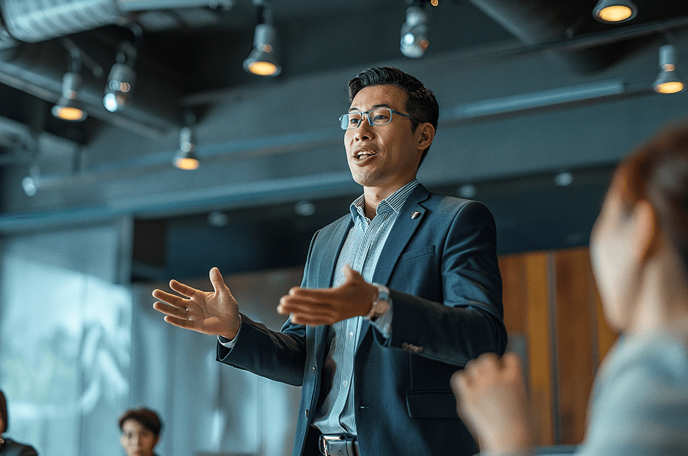 Man speaking to audience using hand gestures  