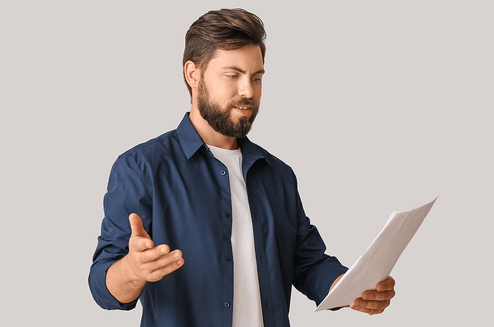 Man in blue shirt holding paper and gesturing while rehearing speech