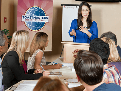 Woman in blue shirt speaking at lectern using hand gesture 