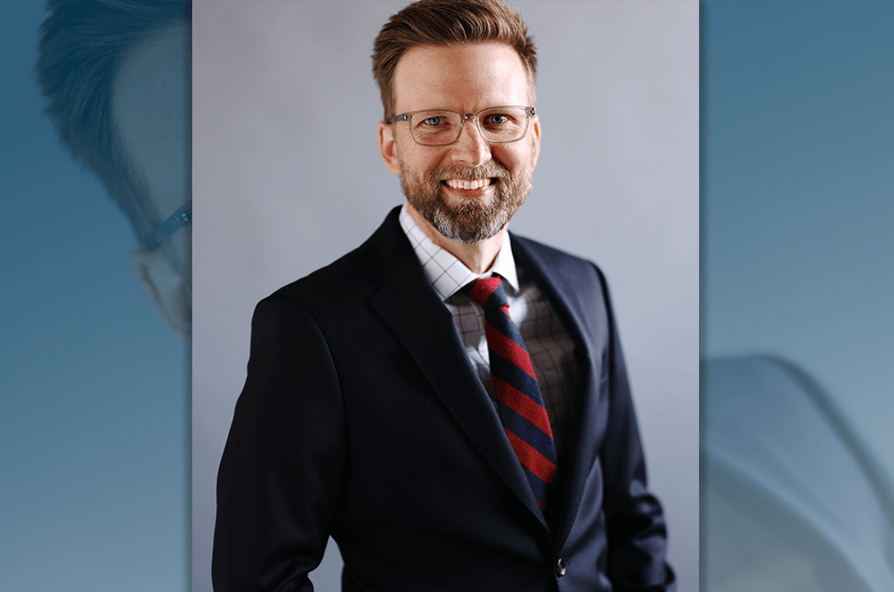 2024 convention keynote speaker Shawn Ellis smiling in jeans jacket and striped red and blue tie