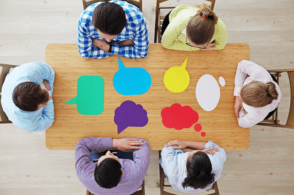 Six people sitting around table with different shapes and colors of chat bubbles