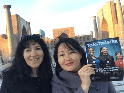 Two women posing outdoors with magazine