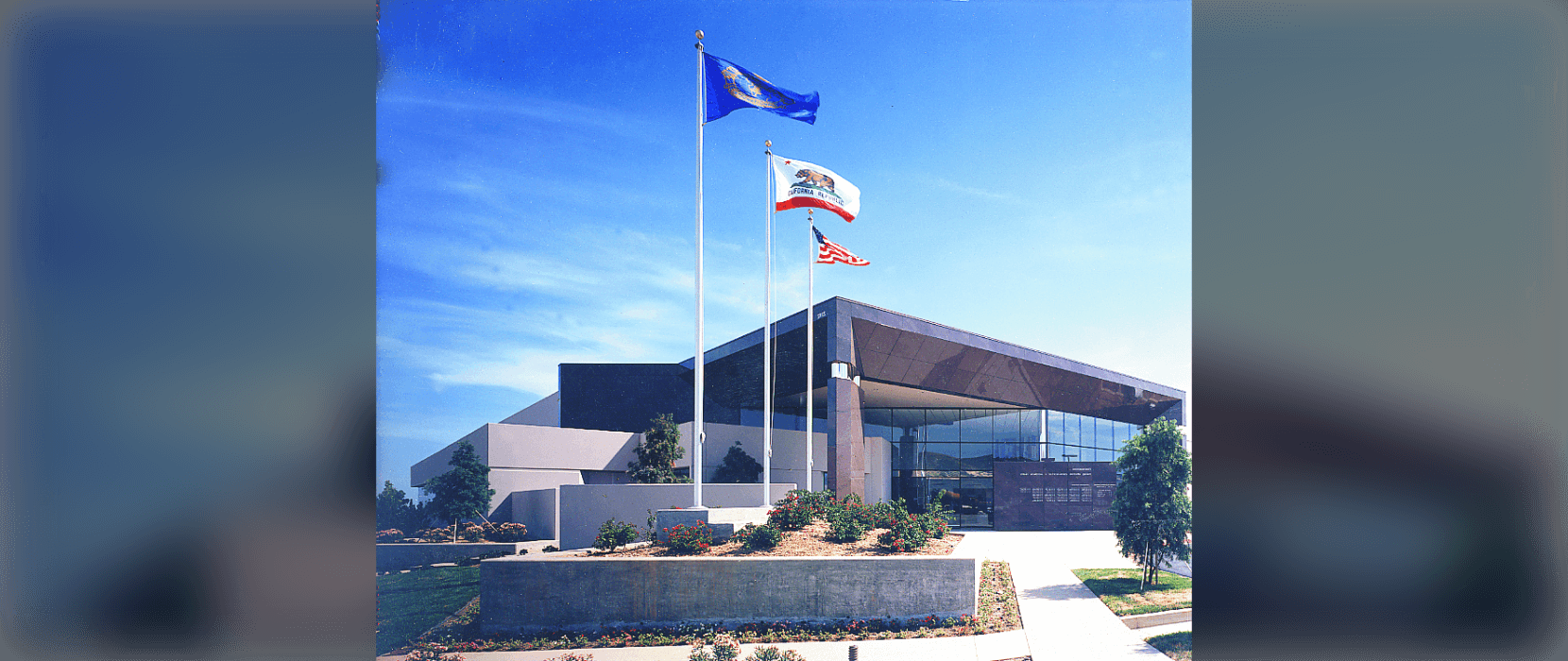 The exterior of a building with three flags on poles