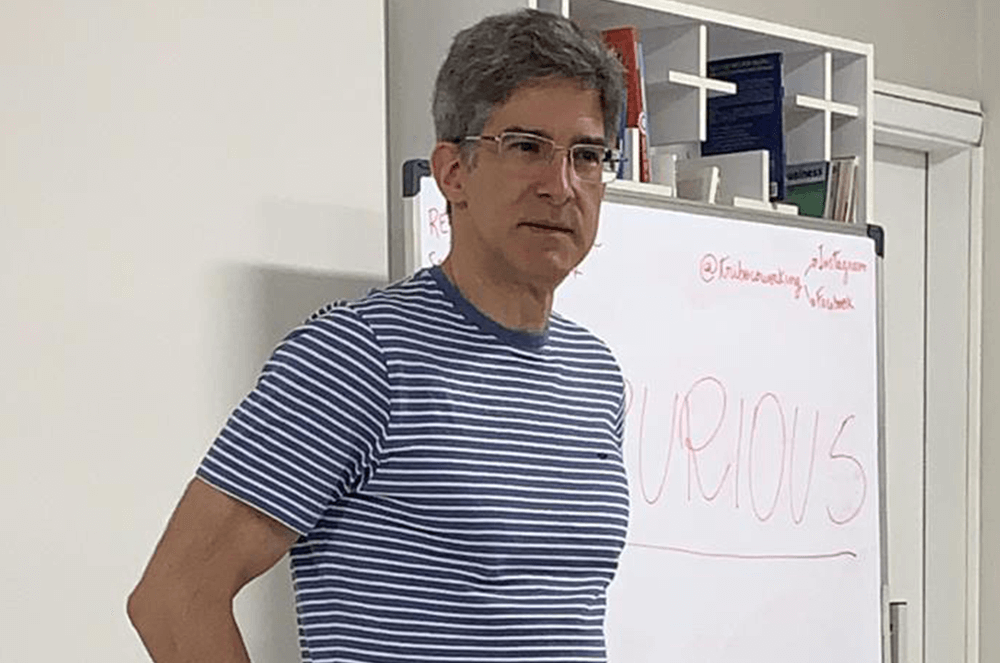 Man wearing glasses and blue and white striped shirt near a white board