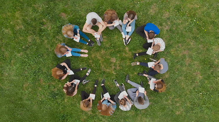 Group of people sitting in circle in grass