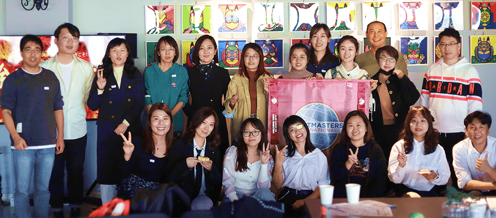 Group of people smiling with Toastmasters banner