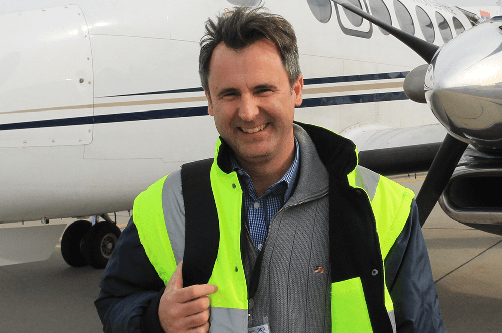 Man in neon green jacket in front of airplane