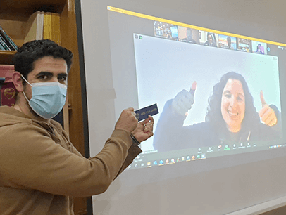 Man holding up ribbon with woman on screen in background