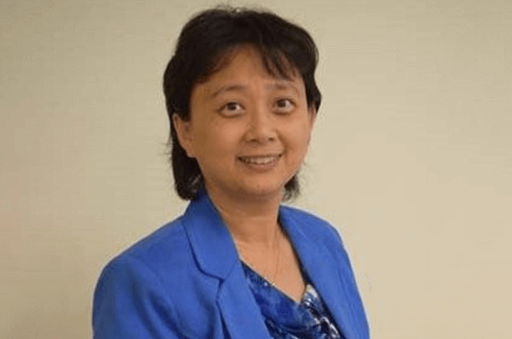 Woman in blue jacket and shirt smiling at camera