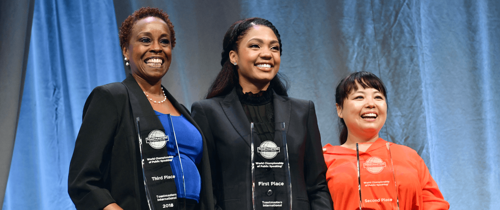 Three women standing with trophies