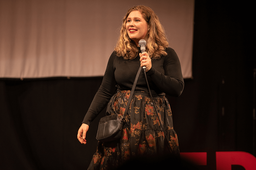 Woman holding microphone while speaking onstage