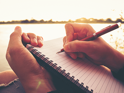 Hand holding pen writing in journal