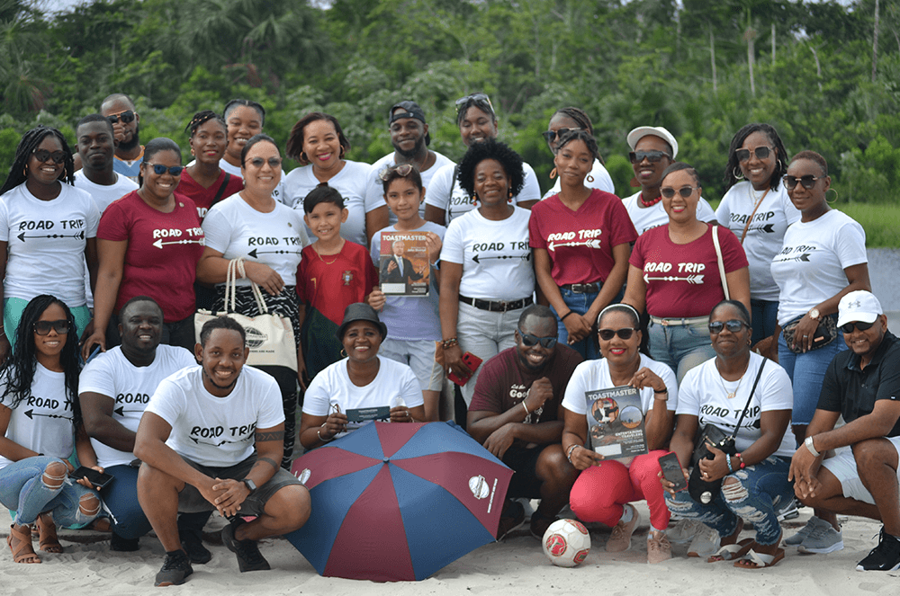 Group of people posing outdoors with Toastmasters umbrella