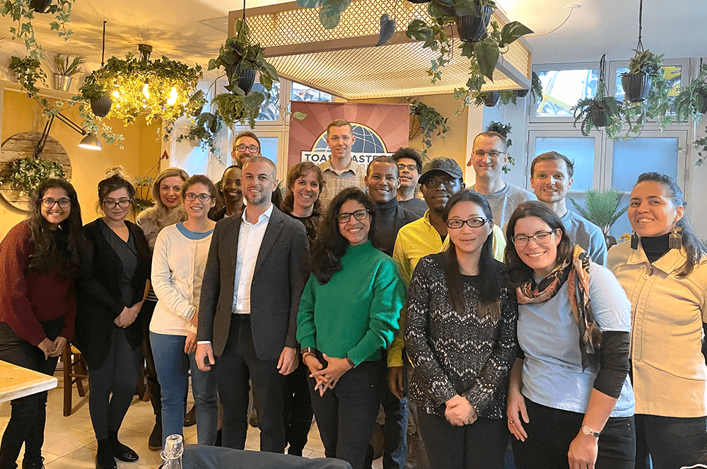 Group of people posing indoors with plants hanging from ceiling