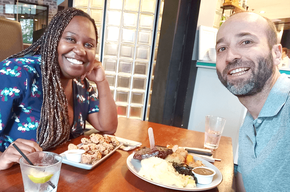 Man and woman posing at table with food