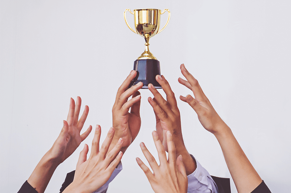 Hands reaching for gold trophy