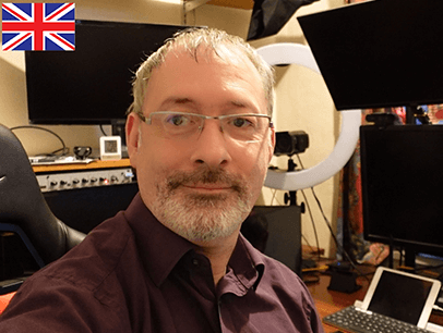 Man looking at camera with computer screens in background