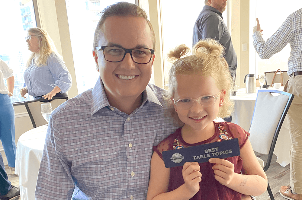 Man and young girl posing with Table Topics ribbon