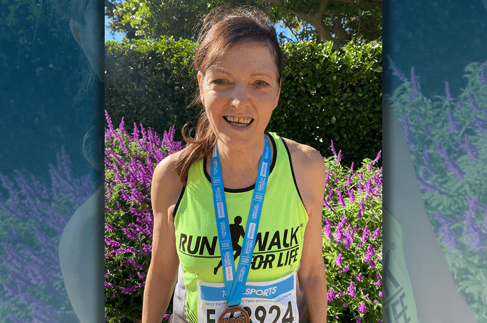 Woman in green tank top wearing medal after running race