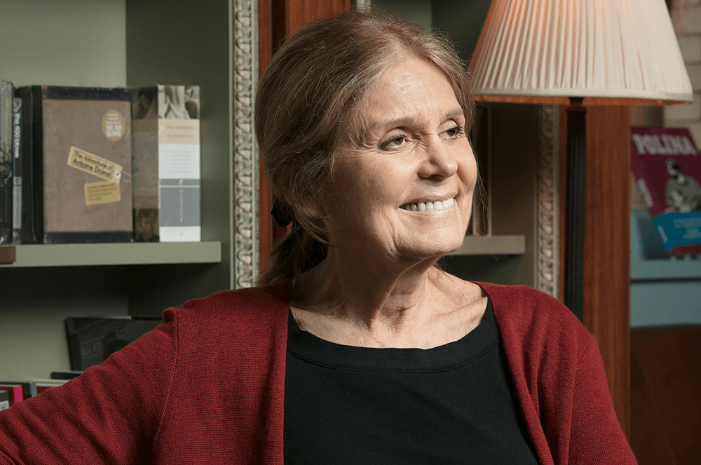 Woman smiling and wearing red cardigan with lamp in background