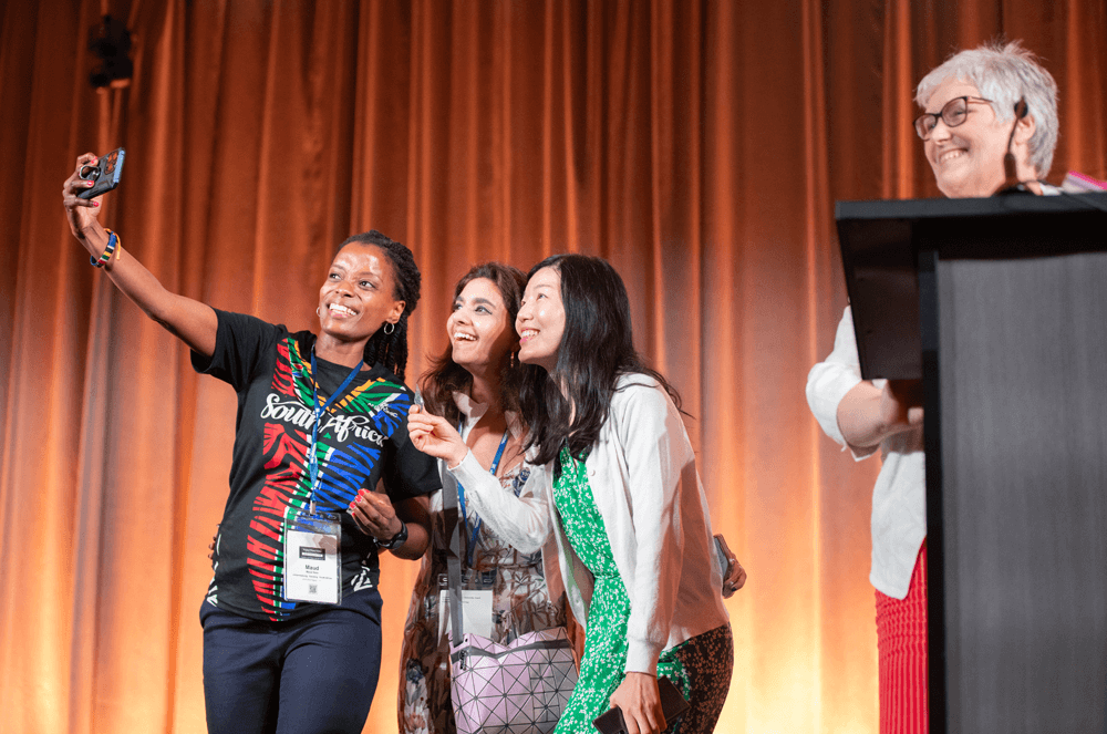 Members share the stage with Immediate Past International President Morag Mathieson, DTM, as they pose for a photo.