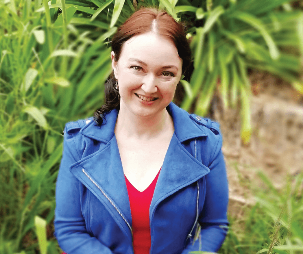 Jolene Stockman smiles in red shirt and blue jacket outside