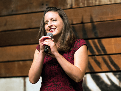 Woman in red dress onstage holding microphone