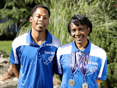 Marcus Chambers and Madonna Hanna pose outdoors in blue and white polo shirts