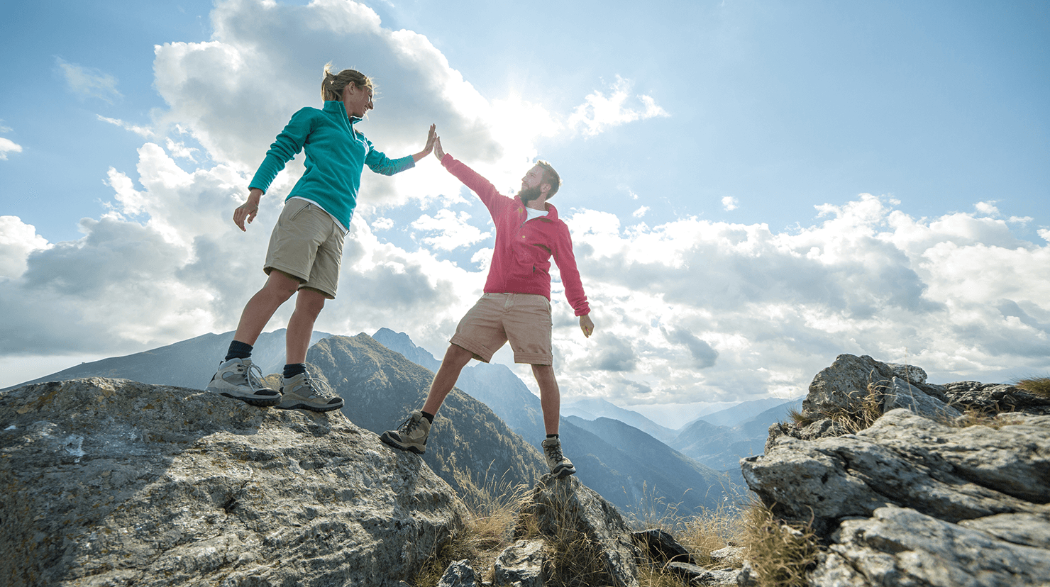 Man and woman high-five on top of mountain