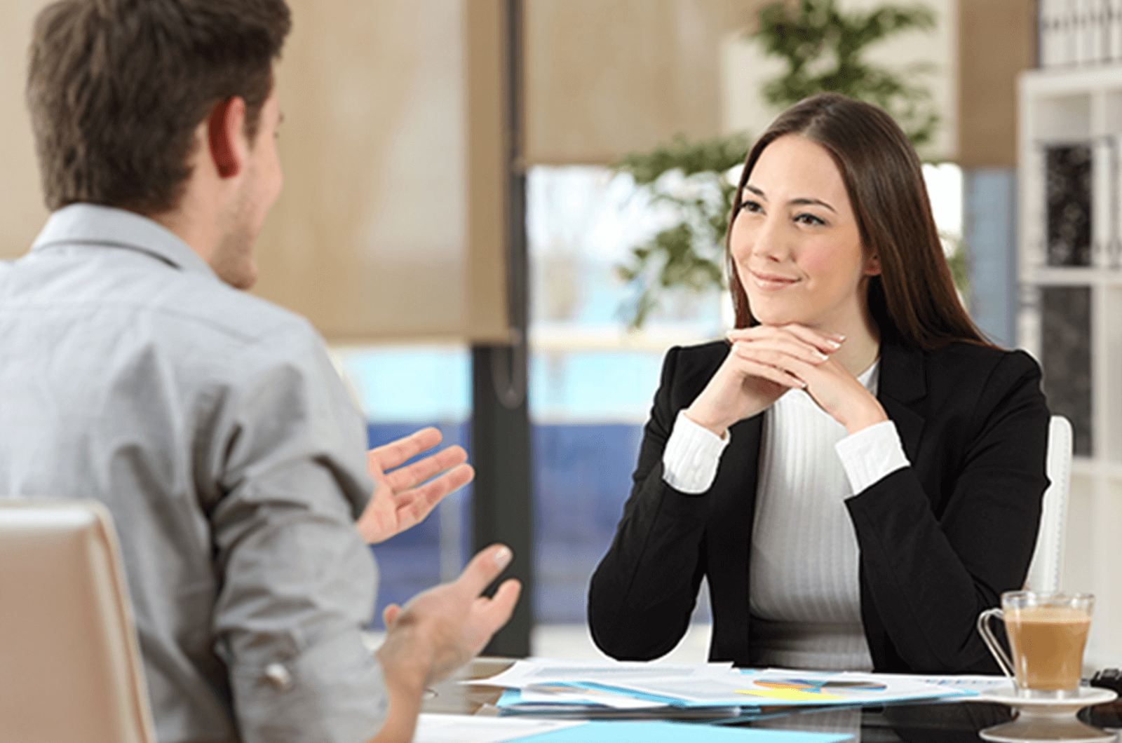 Woman with hands clasped listening to man speak