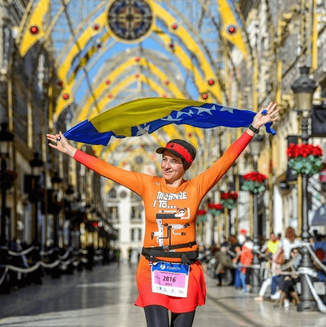 Nudžejma Softić holds the Bosnian flag over her head during a marathon in 2018.