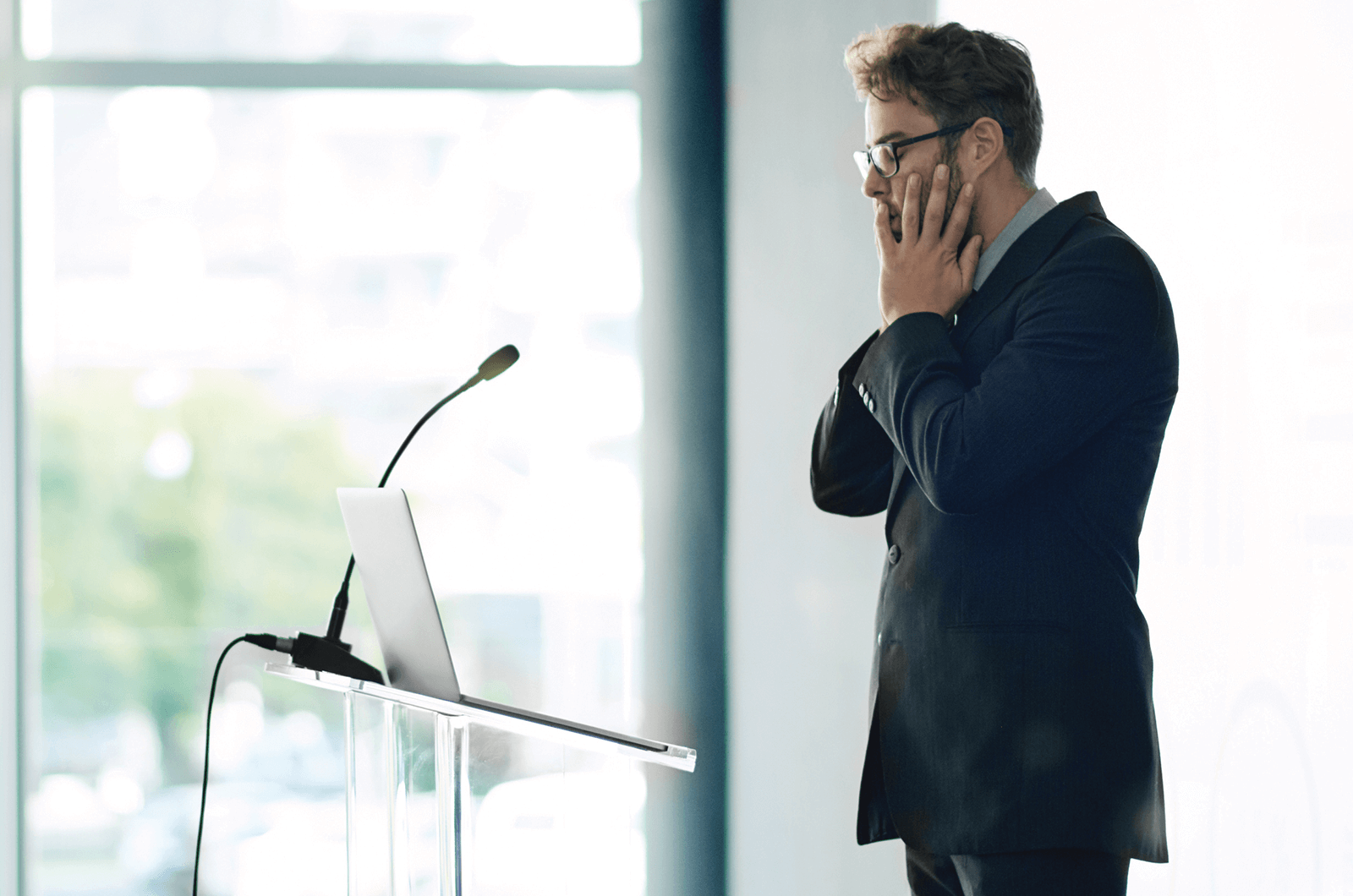 Nervous man standing at lectern with laptop