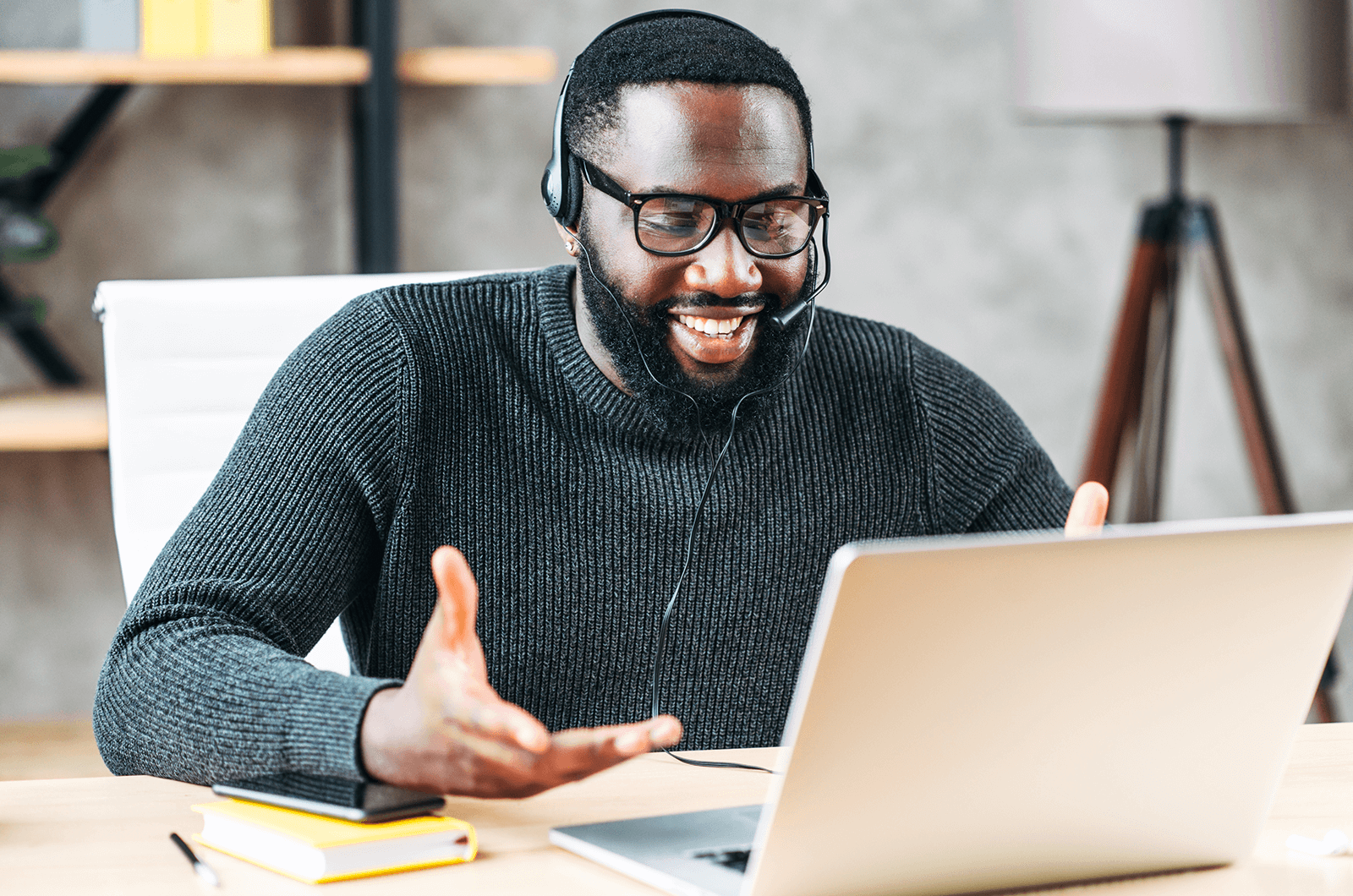 Man wearing headset talking and looking at laptop