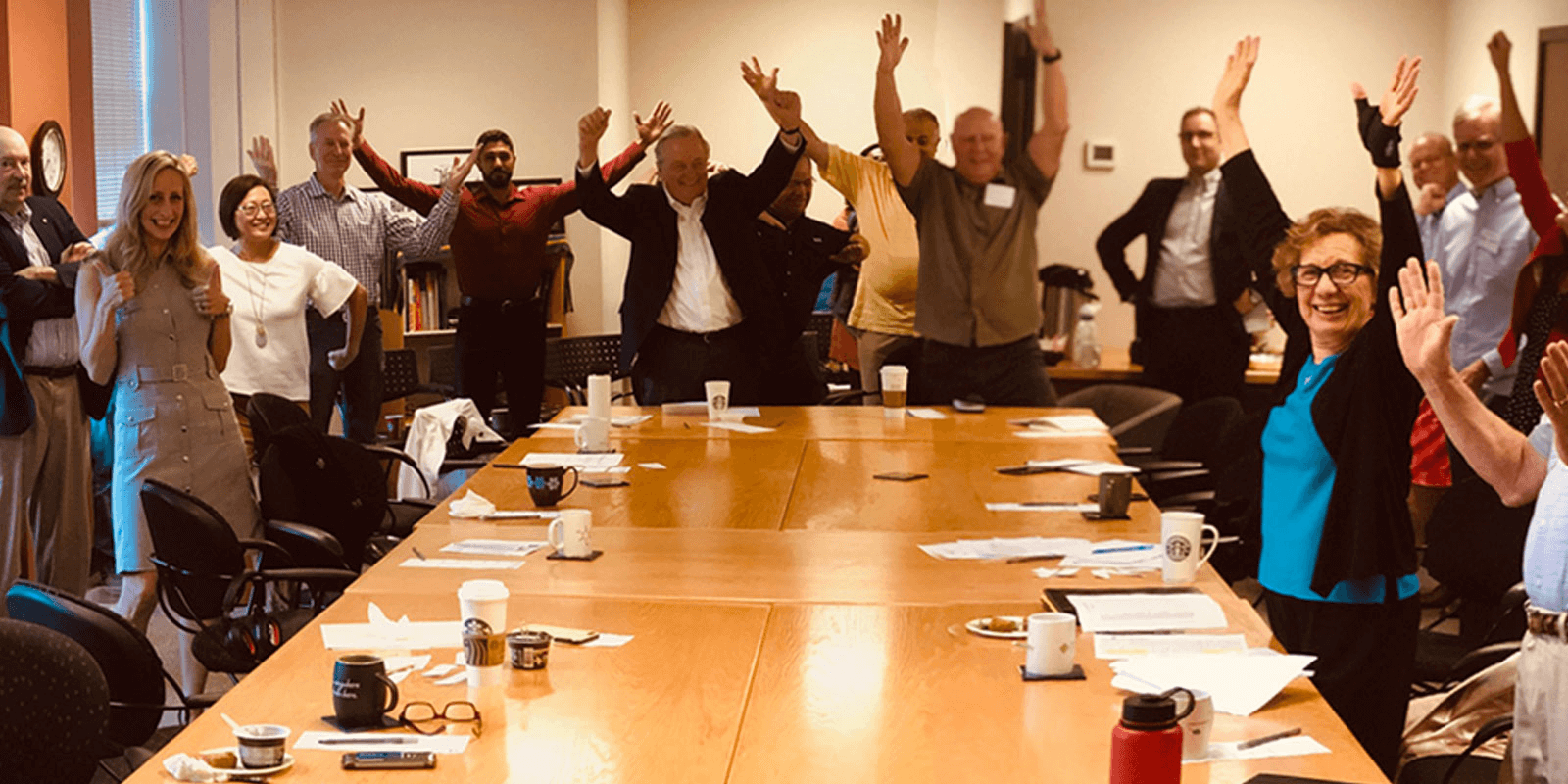 Group of people with arms up in the air around table