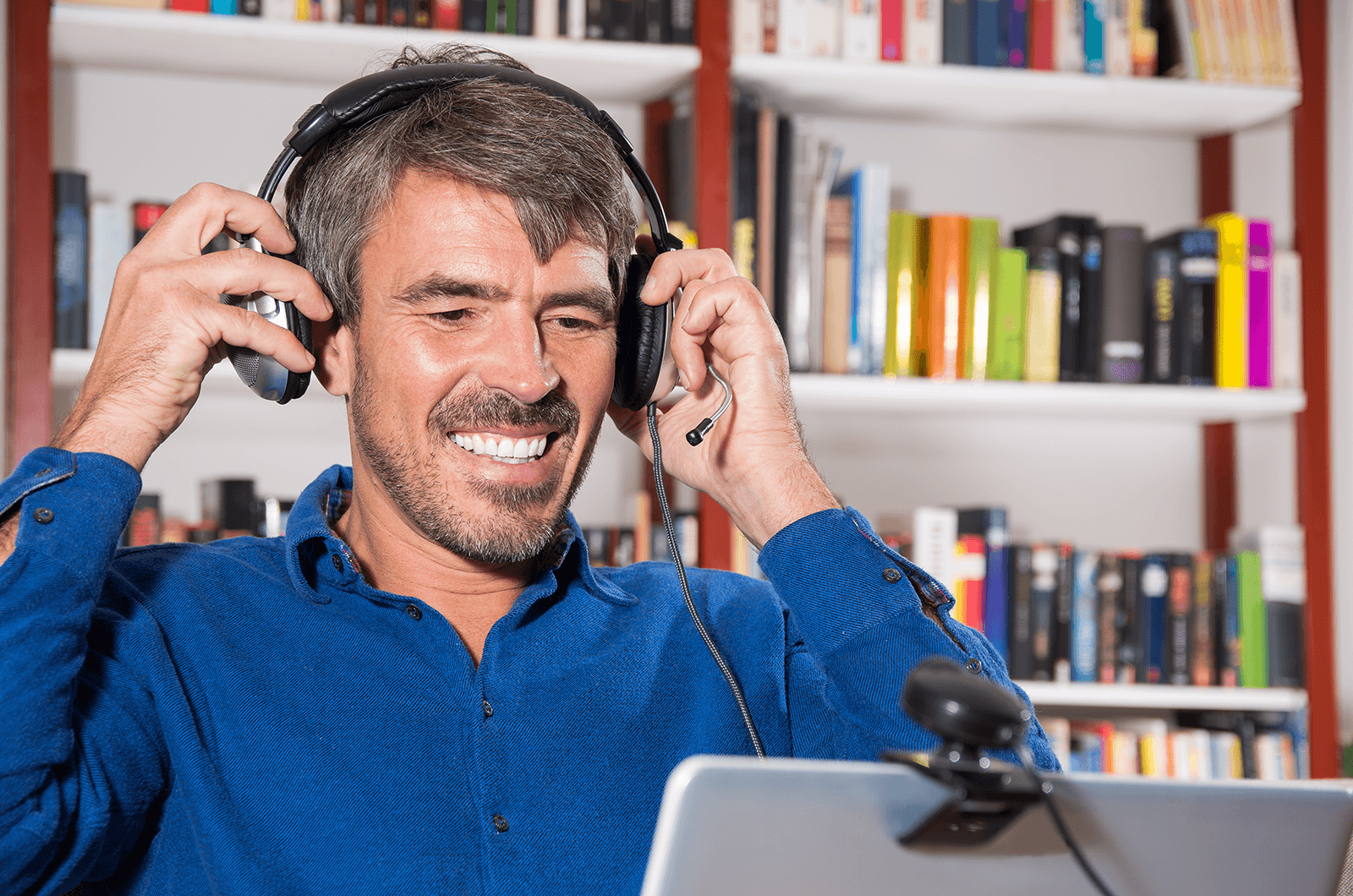 Man in blue shirt adjusting headphones while videoconferencing