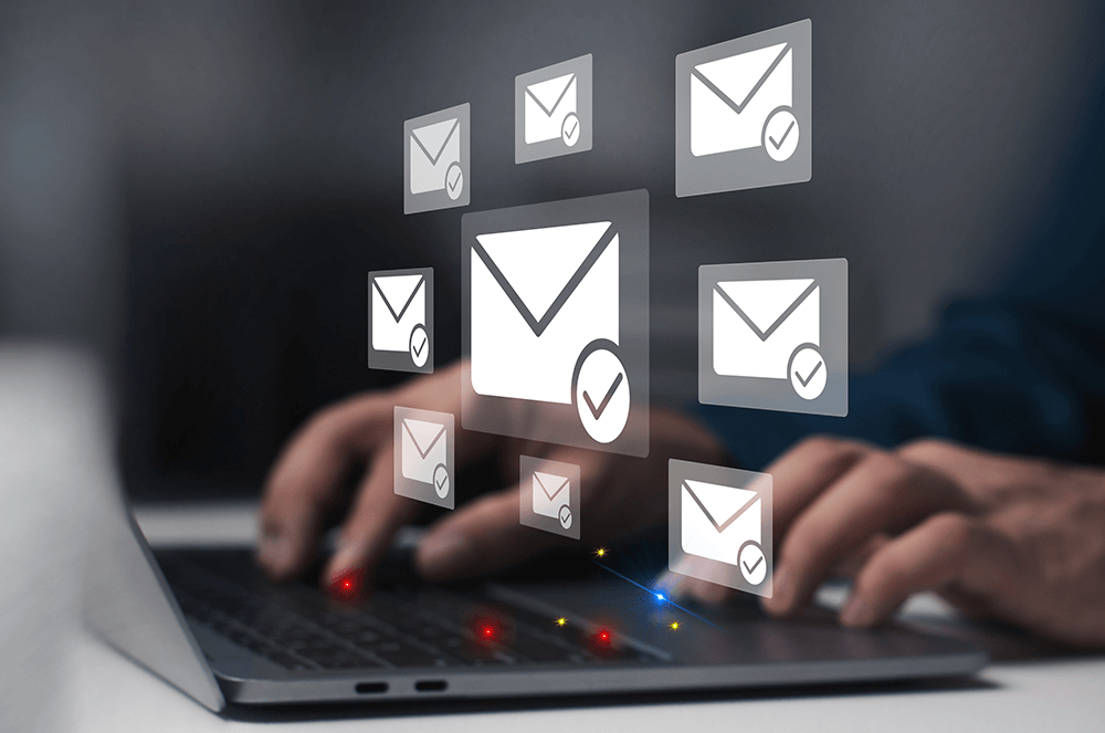 Person typing email on laptop with white envelopes above